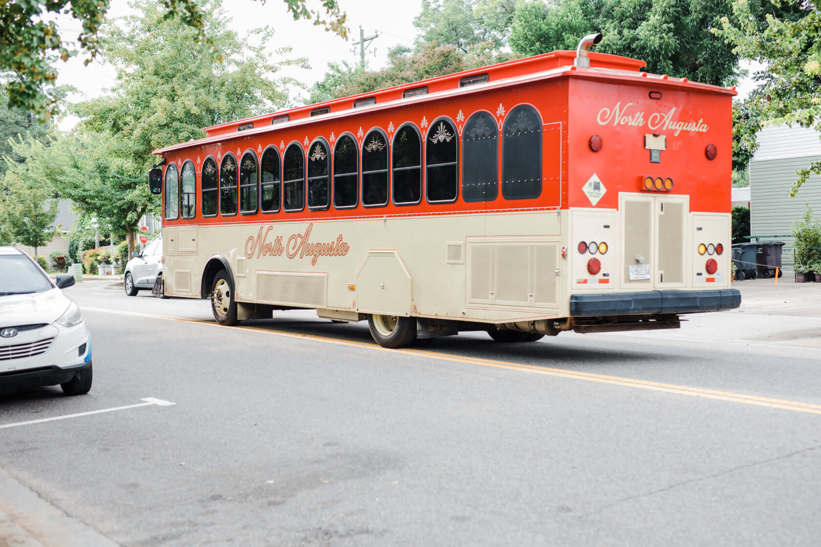The red and tan North Augusta trolley drives away.